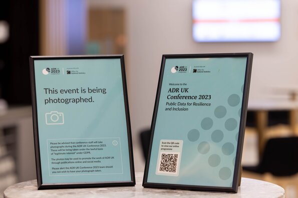 Teal posters which say 'ADR UK Conference 2023' and 'This event is being photographed'