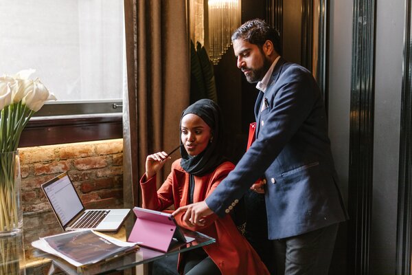 A woman and a man in the office pointing at computer screens
